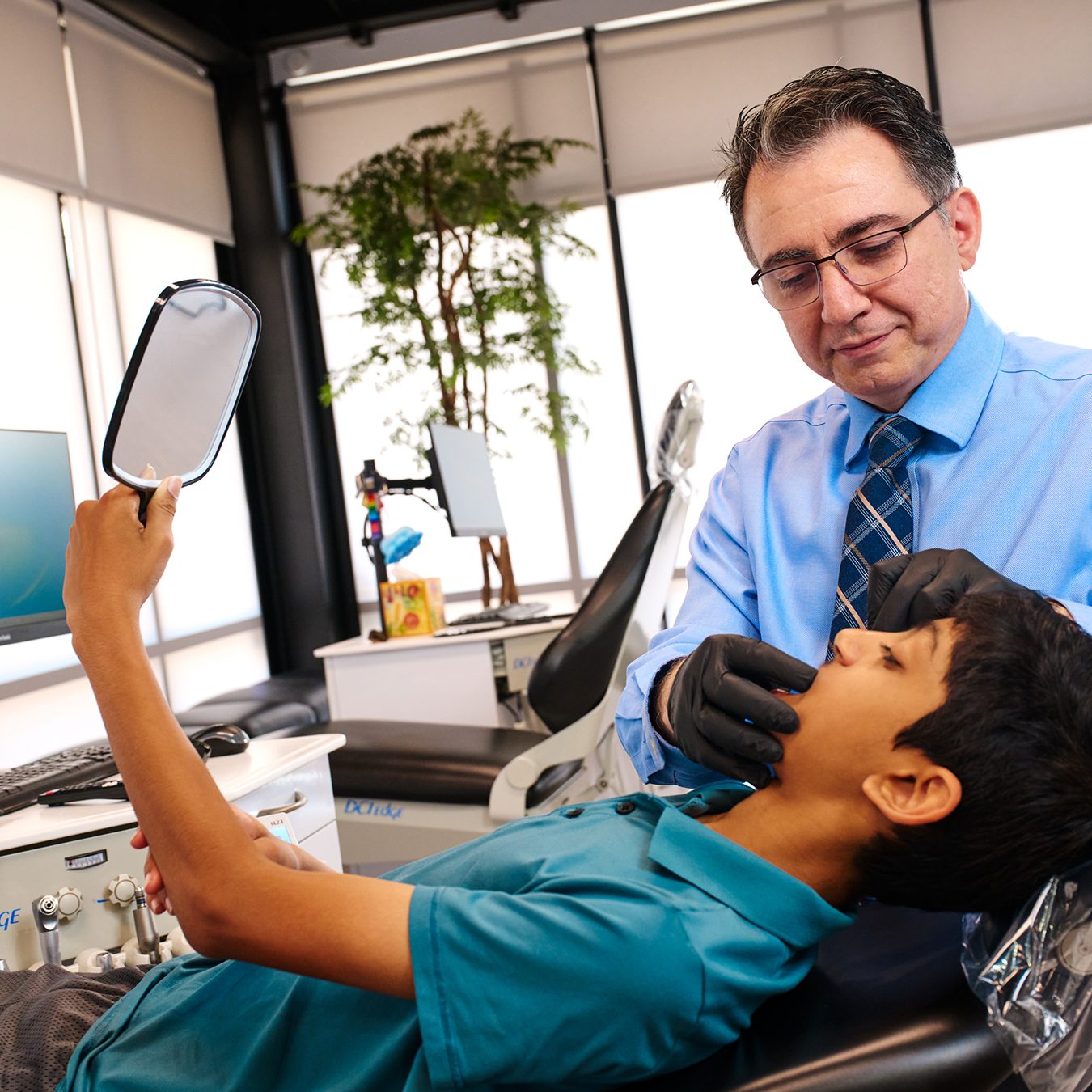 Orthodontist examining young patient's teeth in a modern clinic.