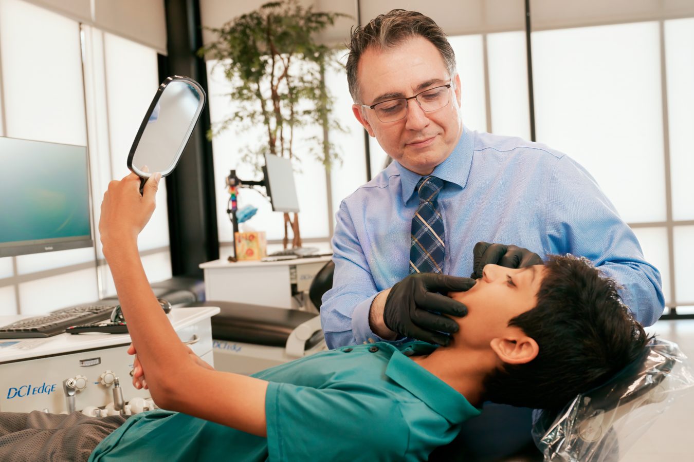 Orthodontist examining a young patient's teeth in a modern clinic.