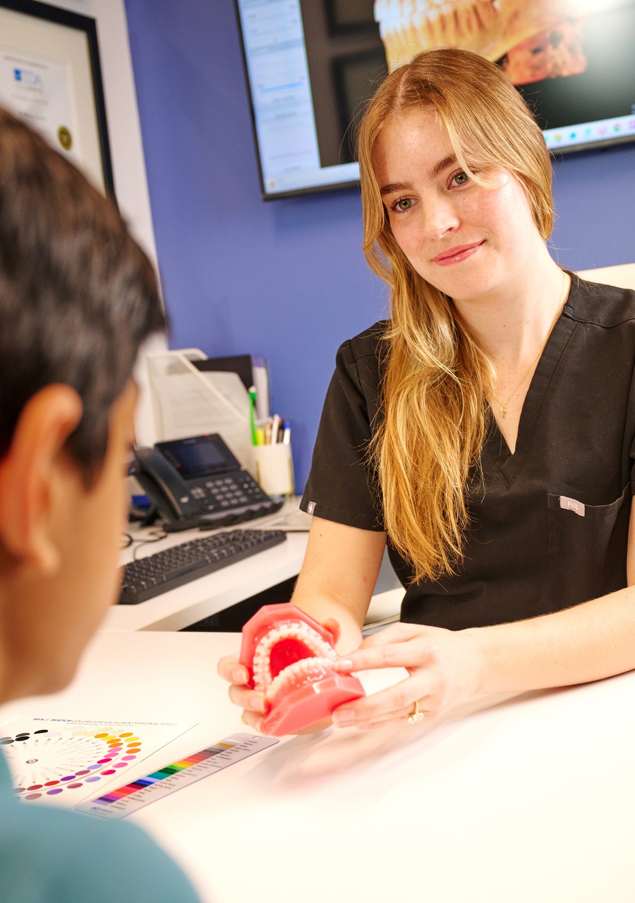 Orthodontist explaining a dental model to a young woman during a consultation