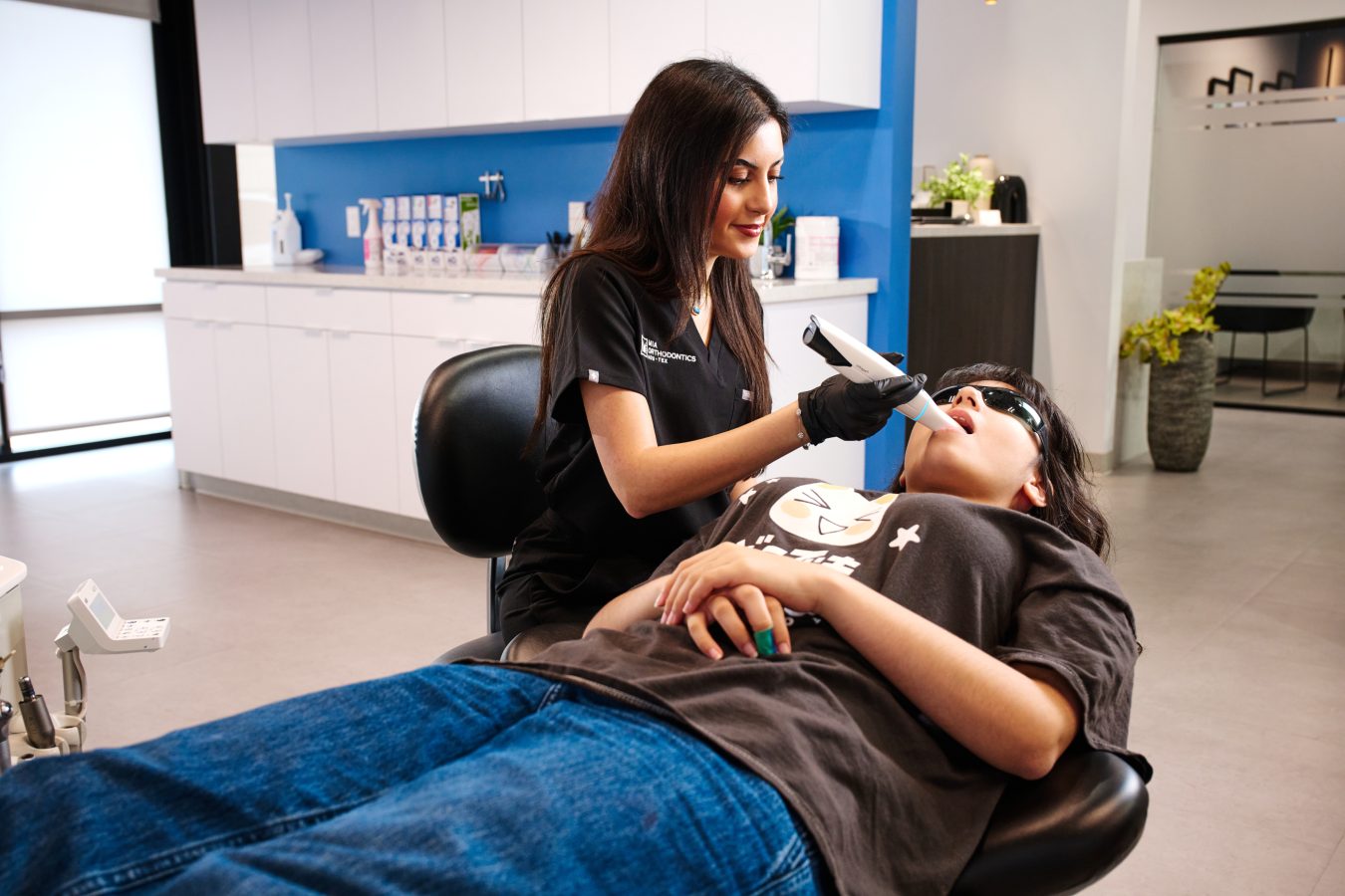 Orthodontist performing dental exam on patient in modern clinic.