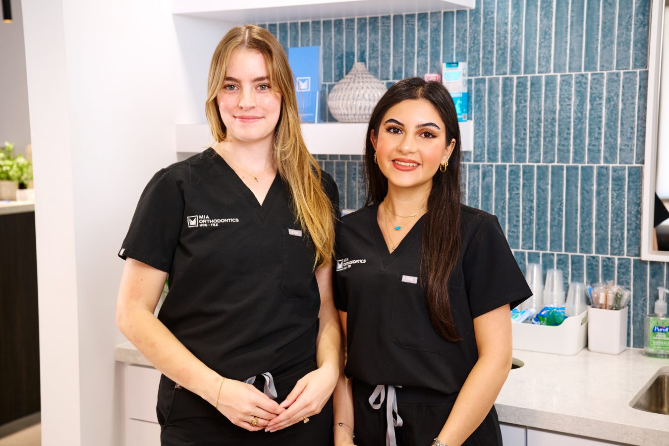 Two smiling orthodontic professionals in black scrubs at Mia Orthodontics.