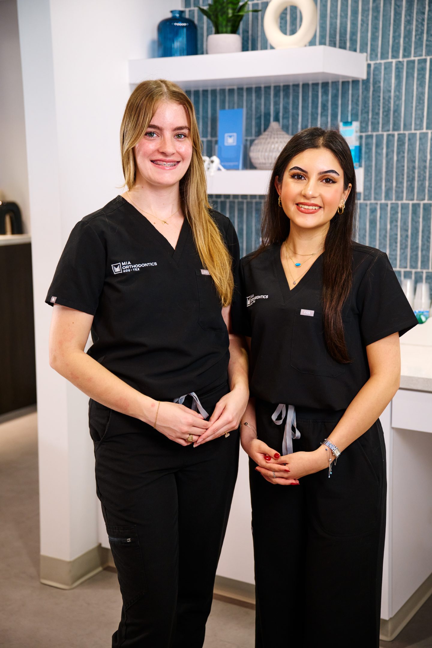 Two smiling orthodontic team members in black scrubs at Mia Orthodontics.